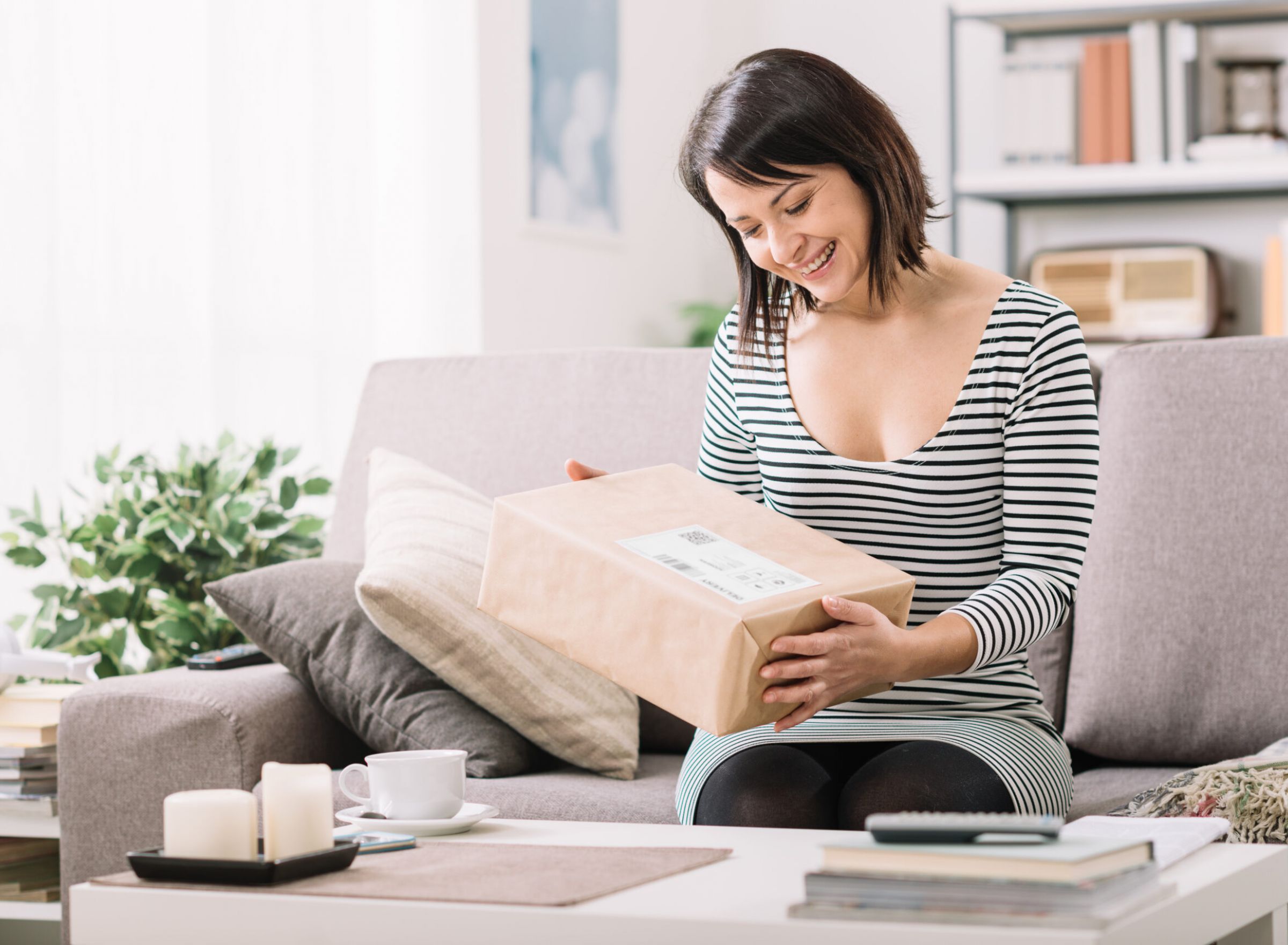 The Delta Pearland luxury apartments Live/Work Spaces with a happy woman opening a mail cardboard package box in a mail lounge