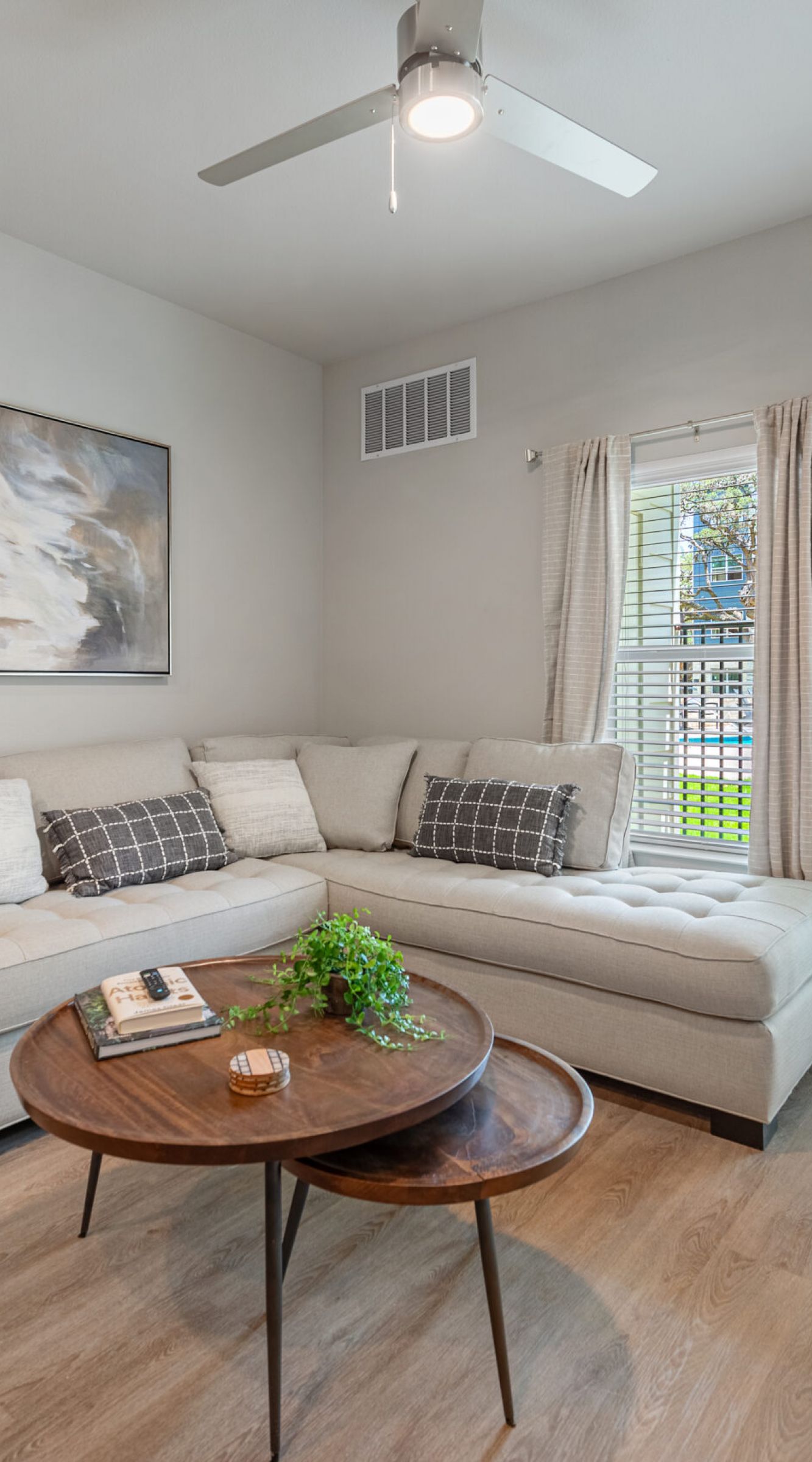 The Delta Pearland living room with wood plank flooring, ceiling fan, large couch, and large windows with lots of natural light