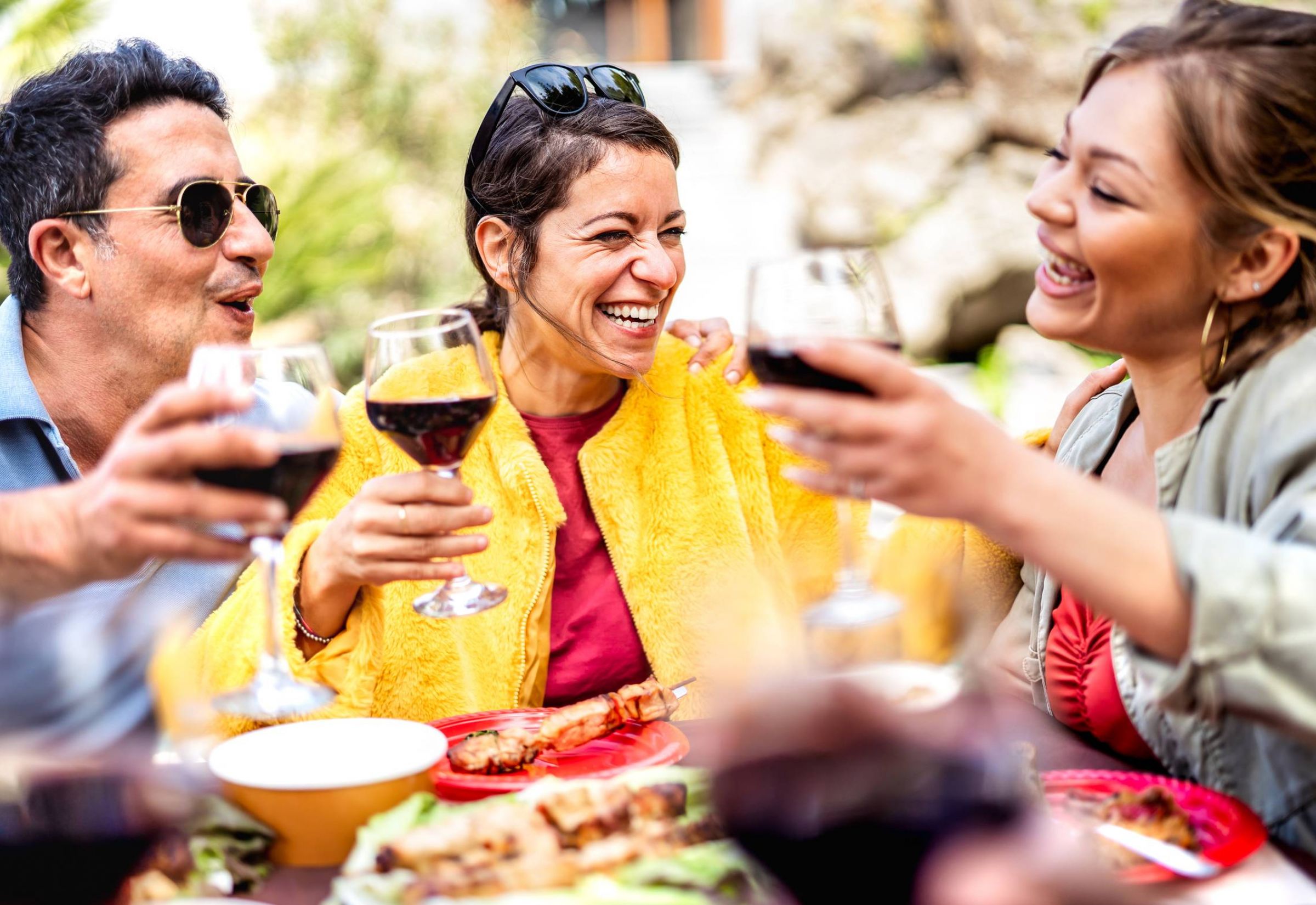 The Delta Pearland Luxury Apartments in Texas neighborhood with happy friends drinking red wine dining on a restaurant patio