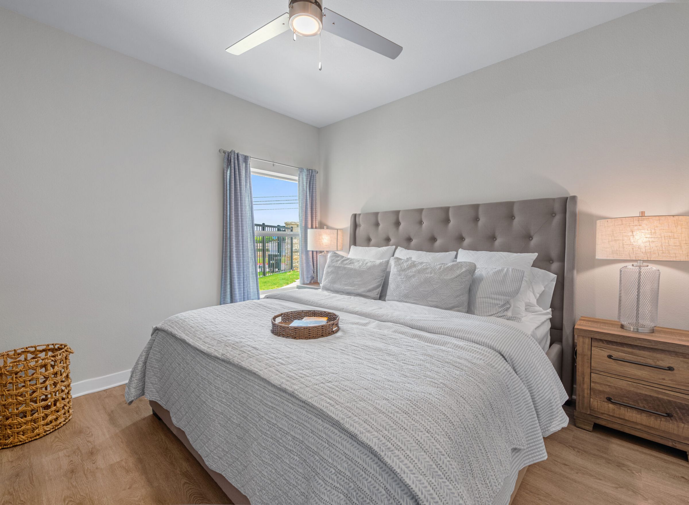 The Delta Pearland apartment bedroom with a large bed, large mirror and large window letting in natural light