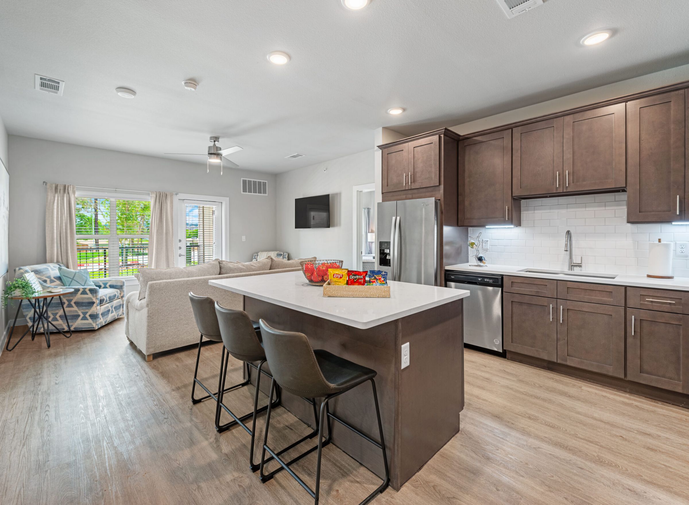 The Delta Pearland kitchen with island, bar chairs, stainless steel appliances, and vinyl plank hardwood-style flooring