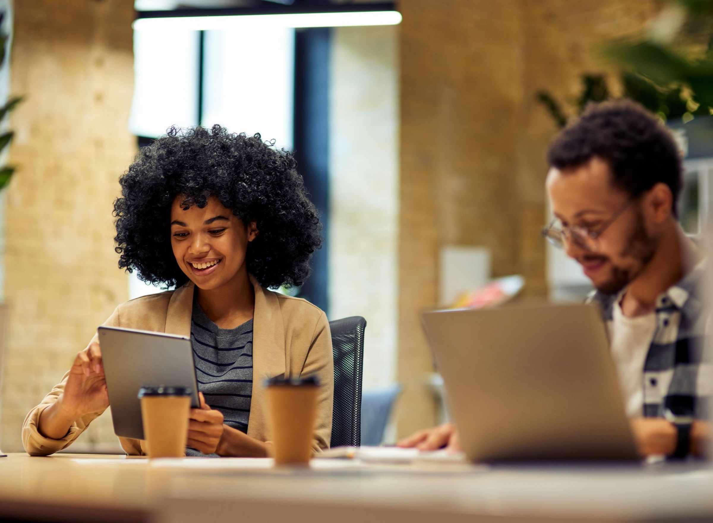 The Delta Pearland luxury apartment community with two smiling friends working on tablets in a co-working space