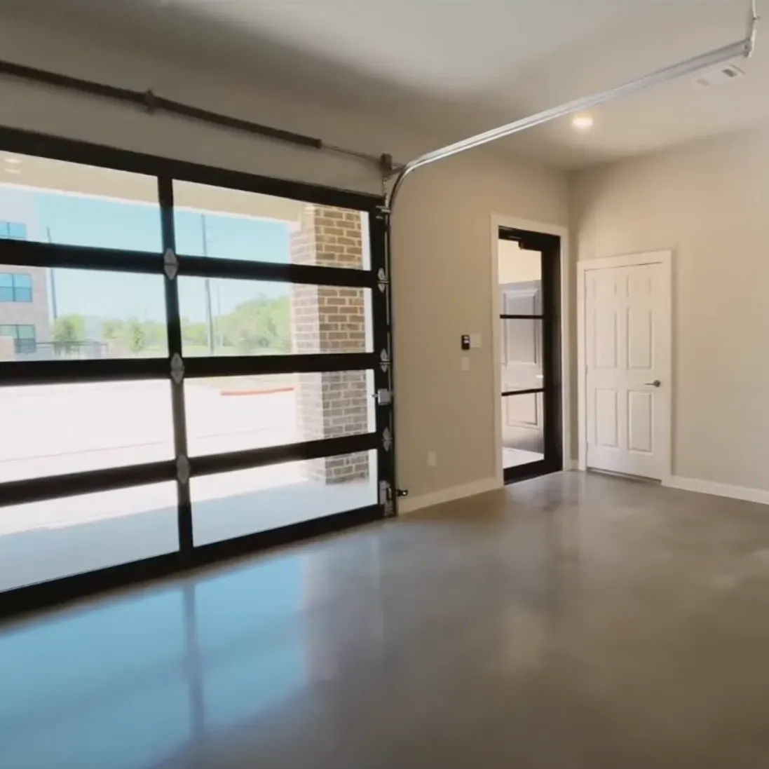 The Delta Pearland Live&Co Suites business and live spaces showing the first floor with a modern empty garage with glass-panel door, white walls, and polished concrete floor, lit by natural light.