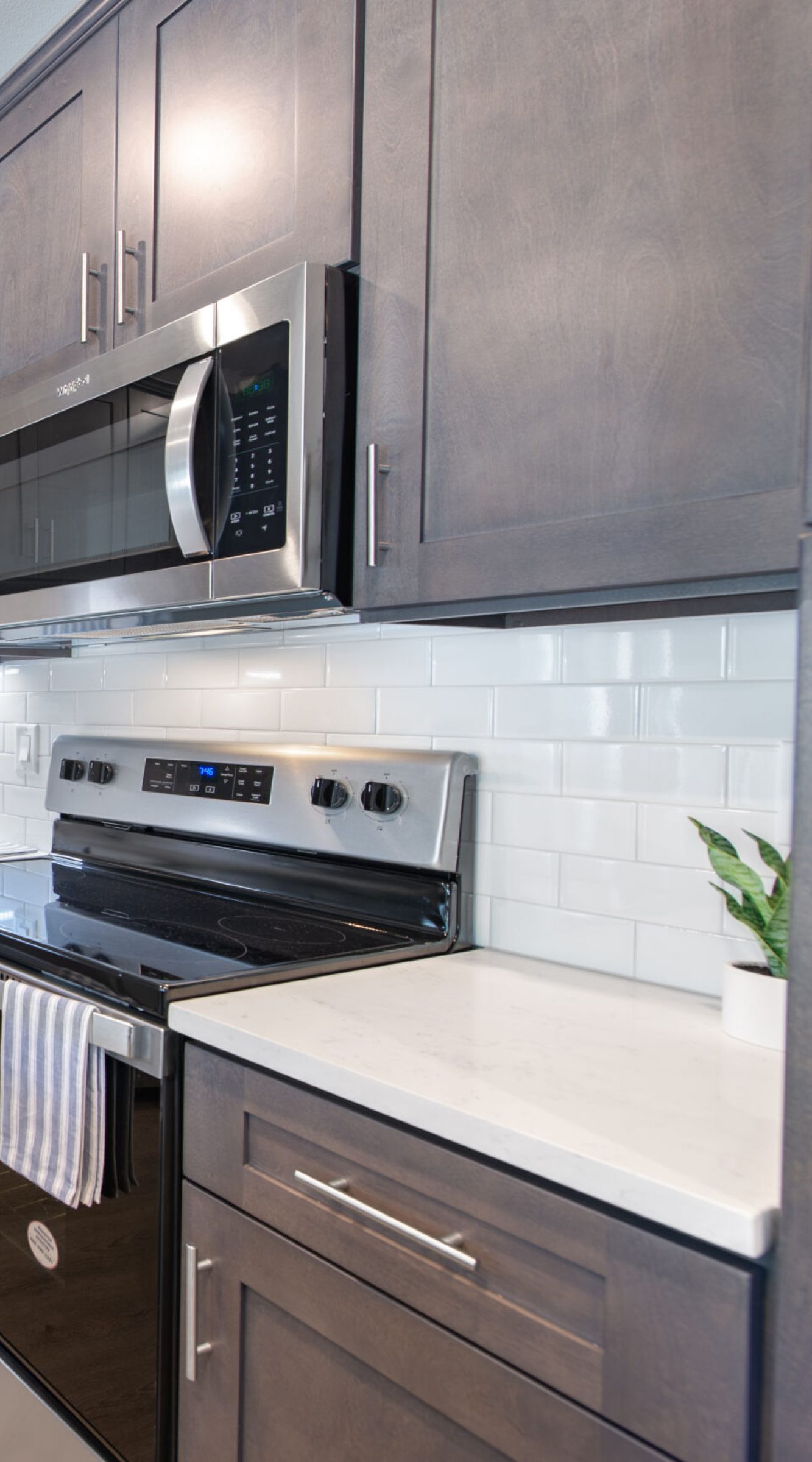 The Delta Pearland kitchen with floor-to-ceiling cabinets, tile backsplash, and hardwood-style vinyl plank flooring